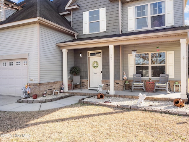 view of exterior entry featuring brick siding, covered porch, and a garage