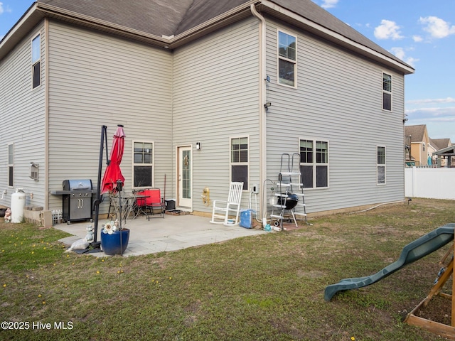 back of property with a yard, a patio, and fence