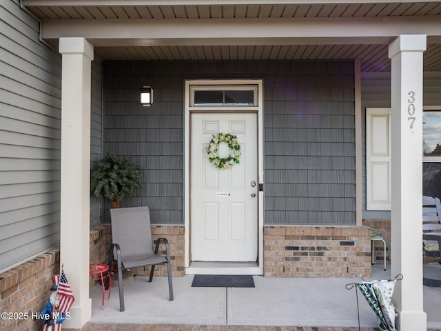 entrance to property with brick siding and a porch