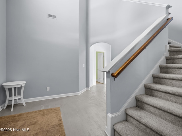 stairs featuring wood finished floors, visible vents, and baseboards