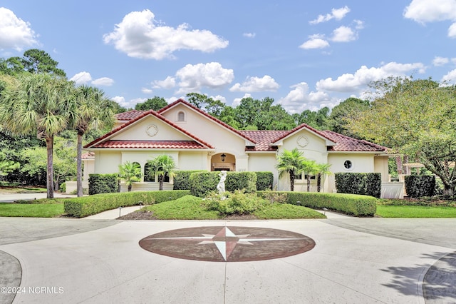 mediterranean / spanish-style home featuring a tiled roof, curved driveway, and stucco siding