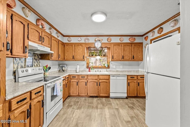 kitchen featuring white appliances, brown cabinets, a sink, and under cabinet range hood