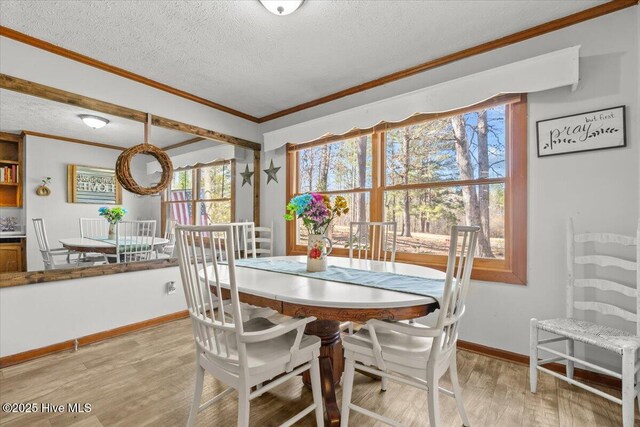 kitchen featuring stainless steel microwave, a textured ceiling, freestanding refrigerator, crown molding, and light wood-style floors