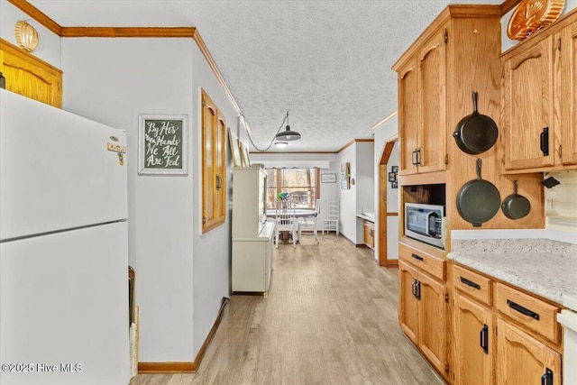 kitchen with stainless steel microwave, ornamental molding, freestanding refrigerator, a textured ceiling, and light wood-type flooring