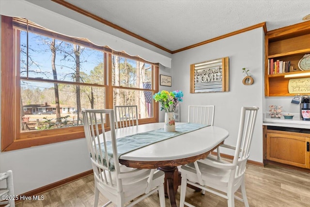 dining space featuring light wood-style floors, baseboards, ornamental molding, and a textured ceiling