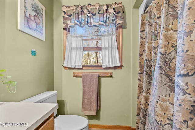 full bathroom with toilet, curtained shower, baseboards, and vanity