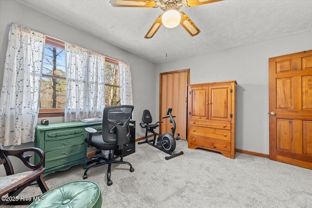 carpeted home office featuring a ceiling fan, baseboards, and a textured ceiling