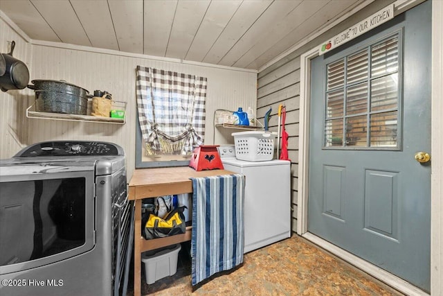 laundry room with wooden ceiling, laundry area, wood walls, and washing machine and clothes dryer