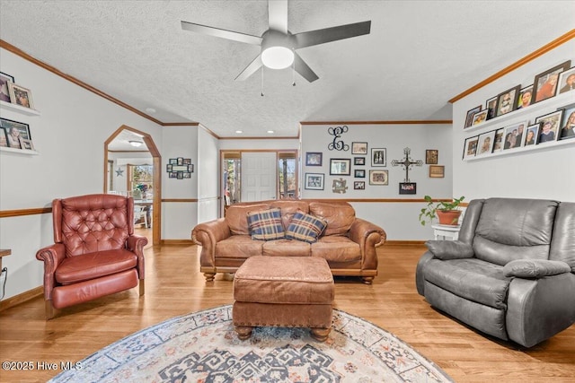 living area featuring a wealth of natural light, a textured ceiling, arched walkways, and wood finished floors