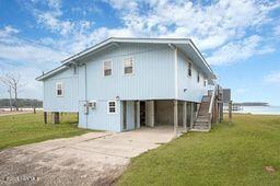 view of property exterior with a yard, a carport, concrete driveway, and stairs