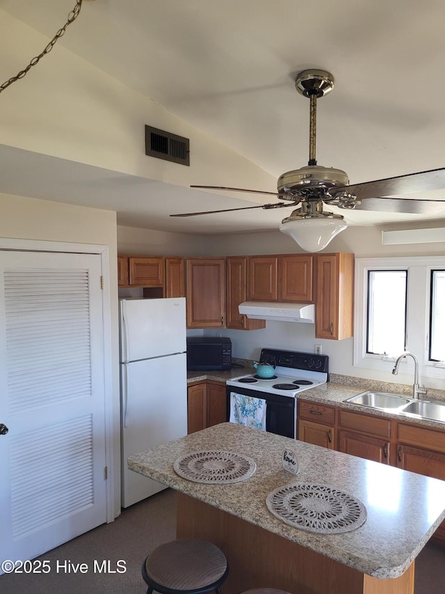 kitchen featuring visible vents, under cabinet range hood, freestanding refrigerator, electric stove, and a sink