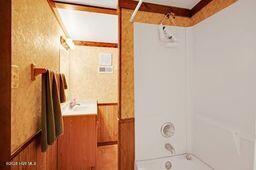 bathroom with tub / shower combination and wainscoting