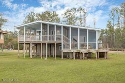 rear view of property featuring a yard and a sunroom