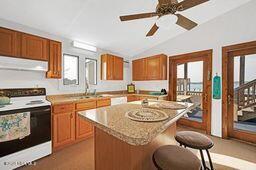 kitchen with electric range, range hood, a breakfast bar, and brown cabinets