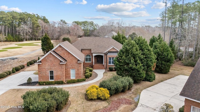 view of front of property featuring roof with shingles, concrete driveway, and brick siding