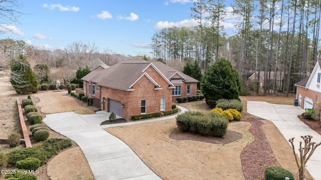 view of front of home featuring a garage, a shingled roof, concrete driveway, and brick siding