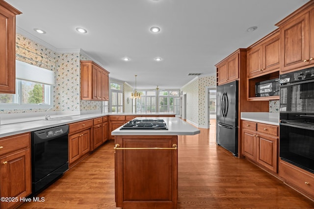 kitchen featuring black appliances, wallpapered walls, crown molding, and wood finished floors