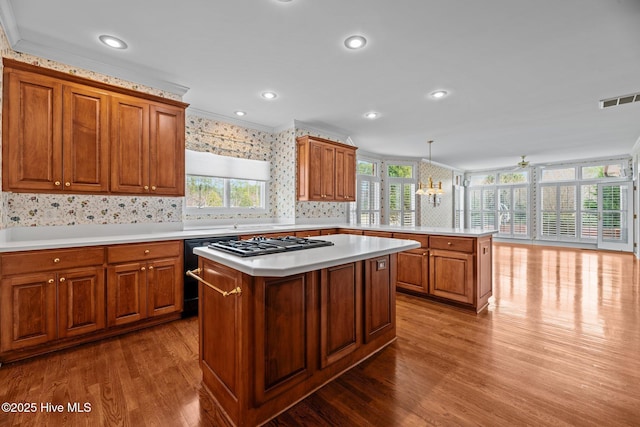 kitchen featuring a peninsula, light countertops, visible vents, and brown cabinets