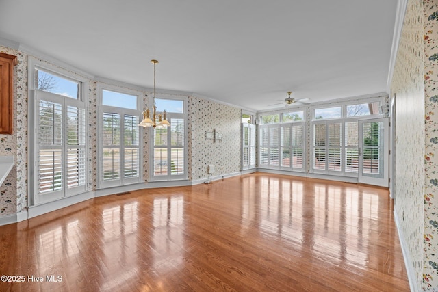 interior space with a wealth of natural light, visible vents, and ceiling fan with notable chandelier