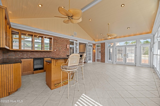 interior space with light tile patterned floors, beverage cooler, dark countertops, ceiling fan, and open floor plan