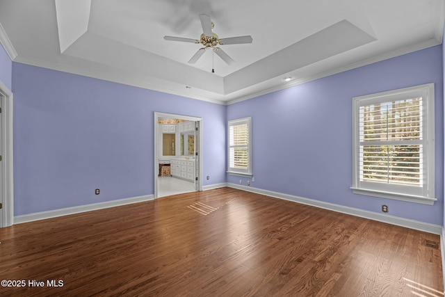 unfurnished room featuring wood finished floors, a ceiling fan, baseboards, ornamental molding, and a tray ceiling