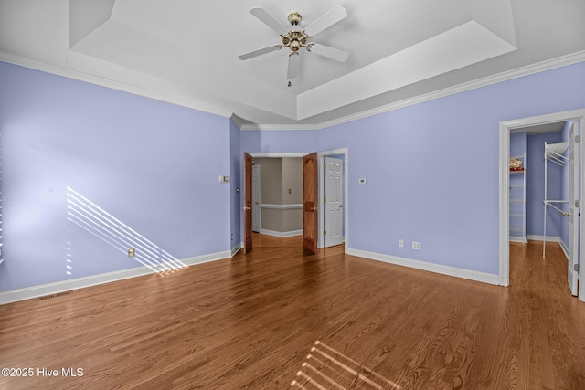 unfurnished bedroom featuring wood finished floors, a raised ceiling, and baseboards