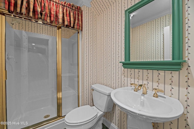 full bathroom with a stall shower, a sink, toilet, and wallpapered walls