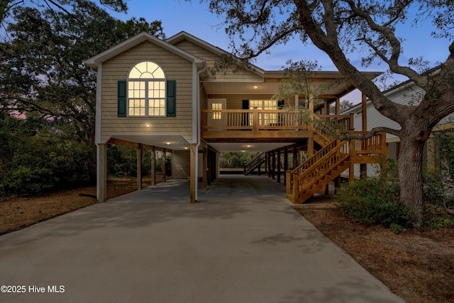 coastal home with covered porch, a carport, stairway, and concrete driveway