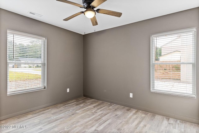 unfurnished room with light wood-style flooring, visible vents, and a wealth of natural light