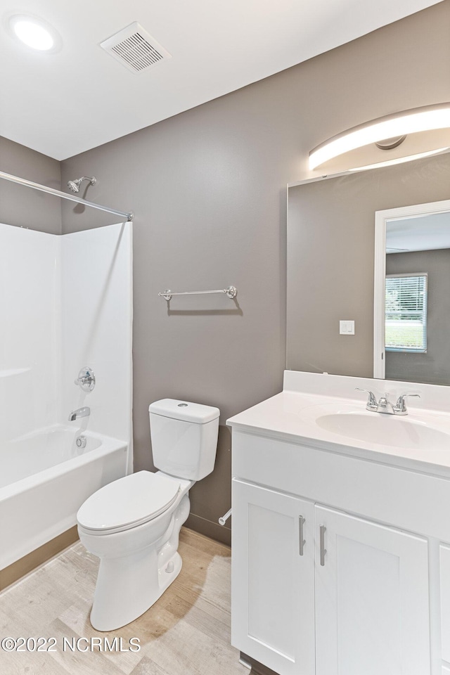 bathroom featuring shower / washtub combination, visible vents, toilet, vanity, and wood finished floors