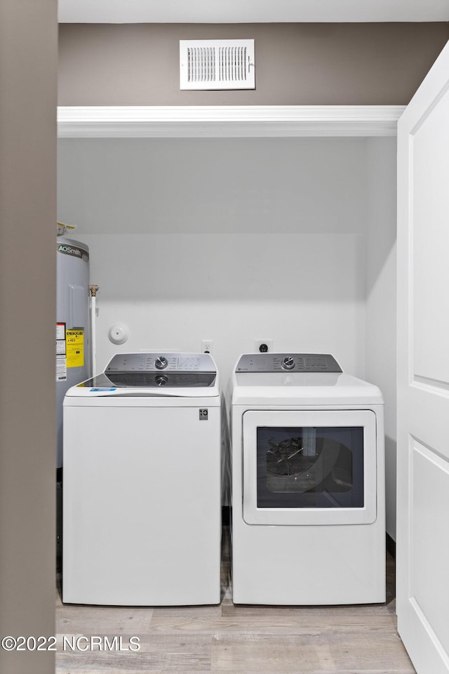 washroom with visible vents, water heater, washing machine and dryer, light wood-type flooring, and laundry area