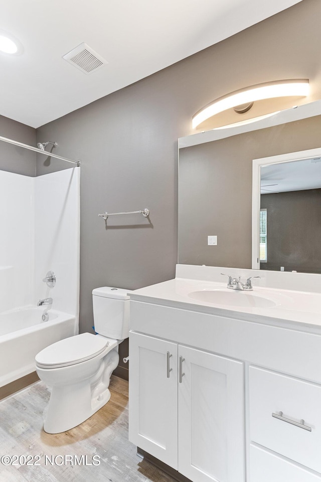 bathroom featuring shower / tub combination, toilet, wood finished floors, vanity, and visible vents