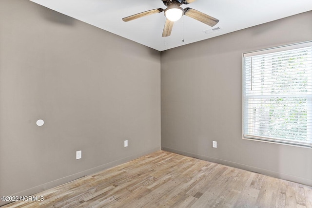 empty room featuring light wood finished floors, ceiling fan, a wealth of natural light, and visible vents