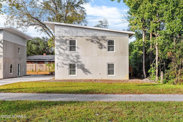 view of side of property with a lawn and fence