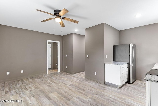 kitchen with light wood-type flooring, freestanding refrigerator, and white cabinets