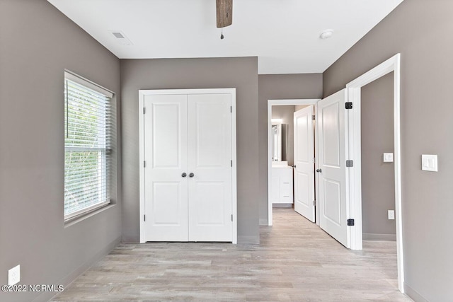 unfurnished bedroom featuring a ceiling fan, visible vents, baseboards, a closet, and light wood finished floors