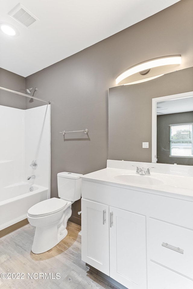 bathroom featuring shower / tub combination, toilet, wood finished floors, vanity, and visible vents