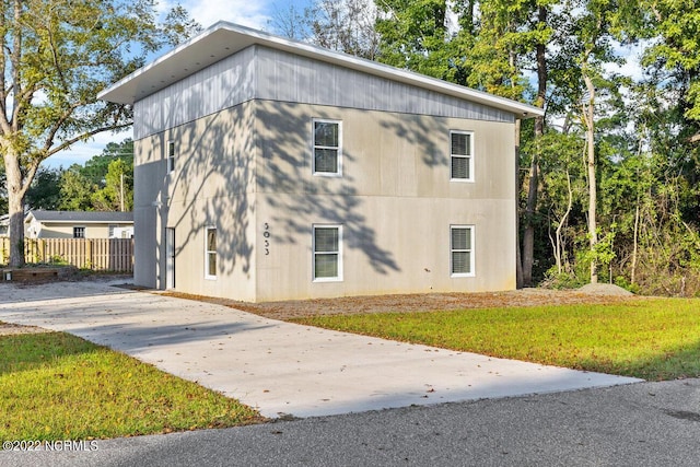 view of side of home with fence and a lawn