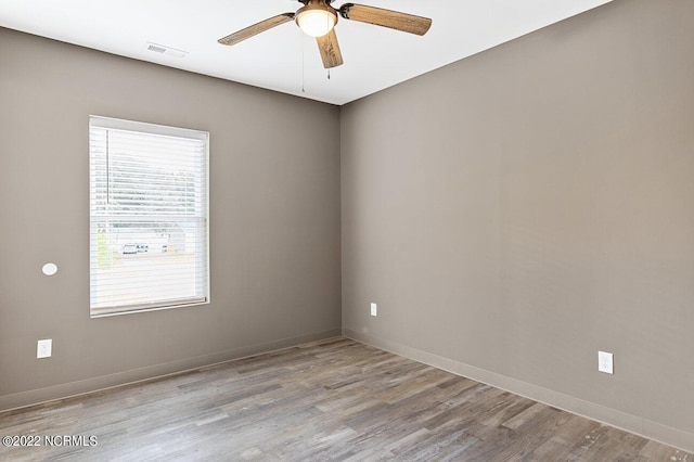 empty room featuring ceiling fan, wood finished floors, visible vents, and baseboards