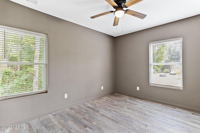 empty room featuring ceiling fan, light wood finished floors, and baseboards