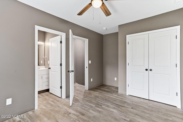 unfurnished bedroom with light wood-type flooring, ceiling fan, a closet, and ensuite bathroom