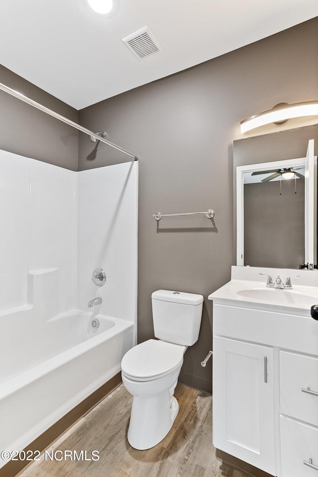 full bathroom featuring visible vents, toilet, washtub / shower combination, vanity, and wood finished floors