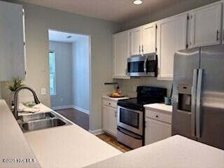 kitchen featuring a sink, baseboards, white cabinets, light countertops, and appliances with stainless steel finishes