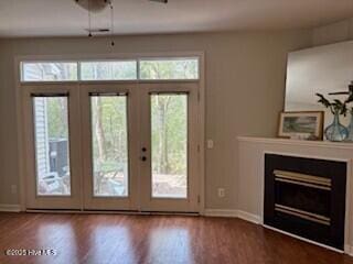 entryway with french doors, wood finished floors, a glass covered fireplace, and baseboards