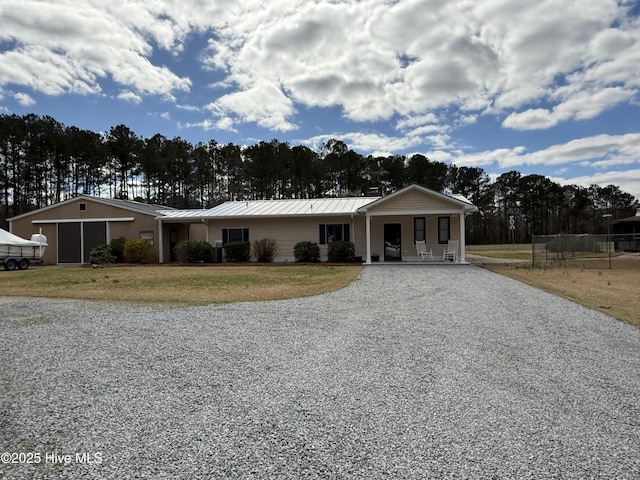 view of front facade featuring metal roof, driveway, a standing seam roof, and a front yard