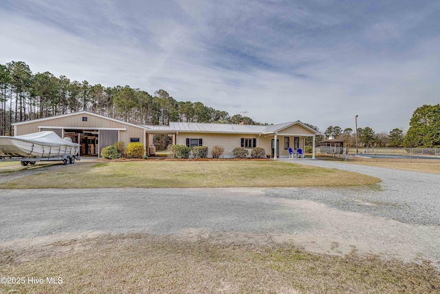 view of front of home with an outbuilding, gravel driveway, and a front yard