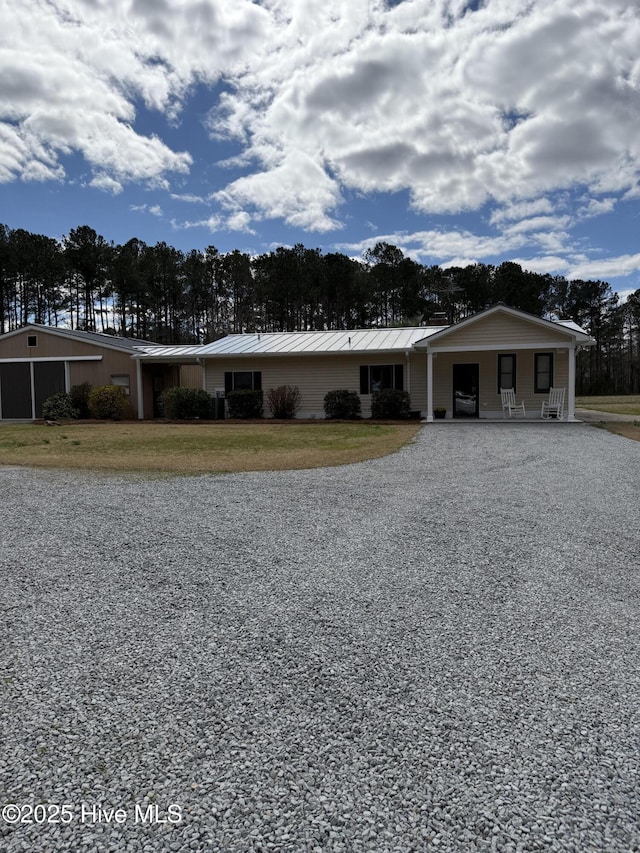 view of front of house featuring driveway, a standing seam roof, metal roof, and a front yard