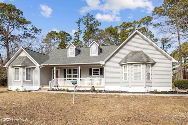 cape cod-style house with a porch and roof with shingles