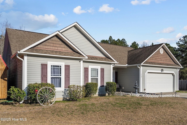 view of front of home featuring driveway, a front lawn, roof with shingles, and an attached garage