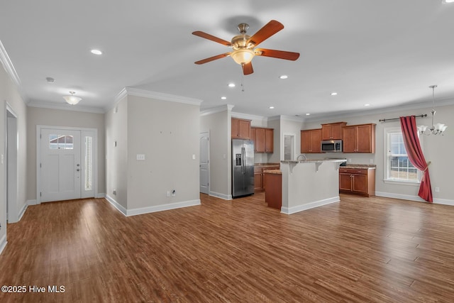 kitchen featuring a breakfast bar, appliances with stainless steel finishes, dark wood-type flooring, open floor plan, and baseboards